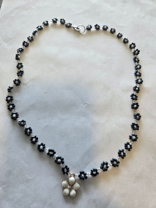 Elegant black and white daisy chain featuring a metal daisy pendant.