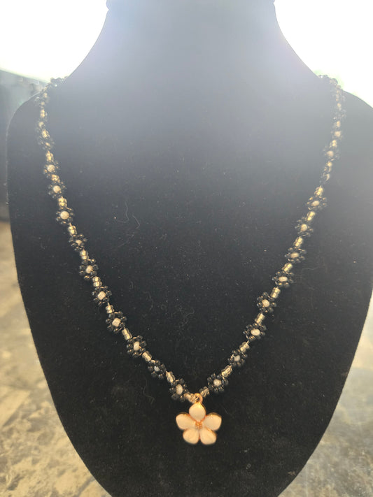 Elegant black and white daisy chain featuring a metal daisy pendant.